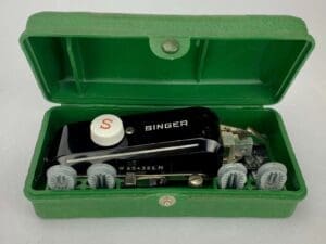 Singer sewing machine accessory in green case.