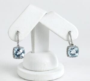 Silver earrings with blue gemstone pendants.