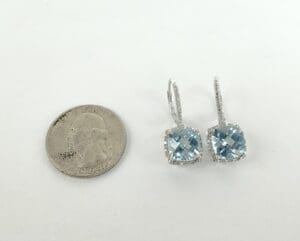Earrings beside a quarter coin for scale.