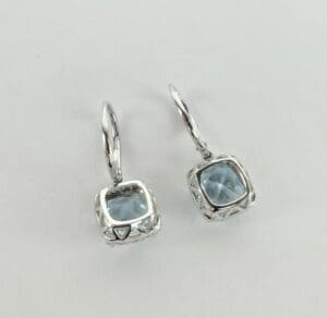 Silver earrings with square blue gemstones.