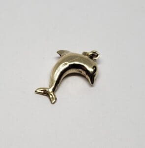 Silver dolphin-shaped charm on white background.