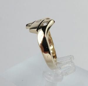 Gold ring with diamond accents on stand.