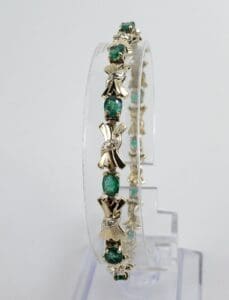 Gold bracelet with green gemstones displayed vertically.