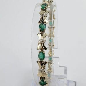 Gold bracelet with green gemstones displayed vertically.