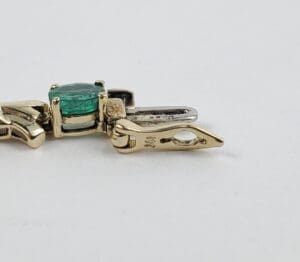 Gold pendant with green gemstone centerpiece.
