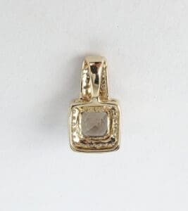 Gold pendant with square gemstone center.