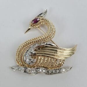 Gold swan brooch with gemstone details.