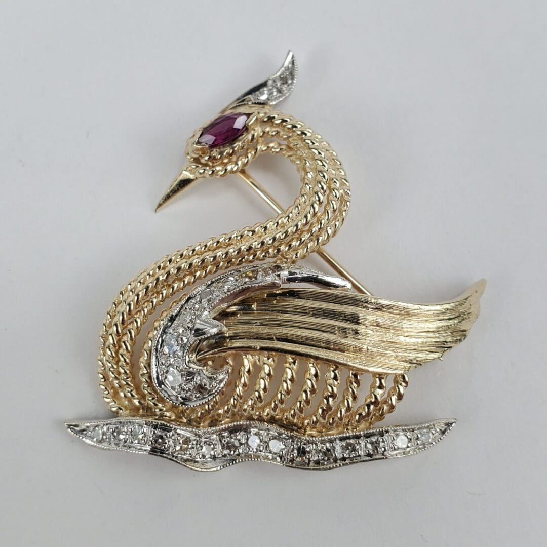 Gold swan brooch with gemstone details.