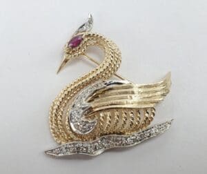 Gold swan brooch with jeweled accents.
