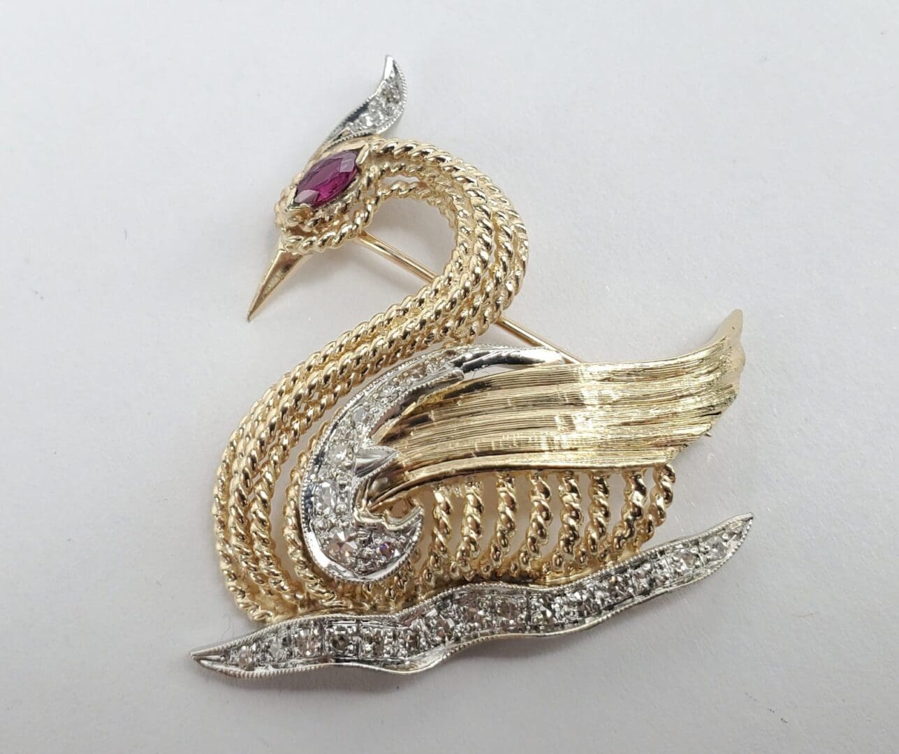 Gold swan brooch with jeweled accents.