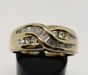 Gold ring with diamonds on black stand.