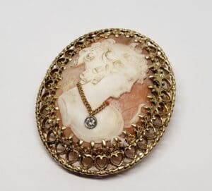 Vintage cameo brooch with intricate gold design.