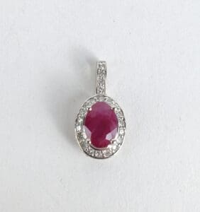 Ruby pendant with diamond accents on white.