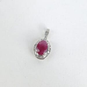 Ruby pendant with diamond accents on white.