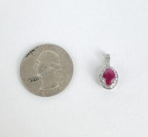 Quarter next to ruby pendant on white background.