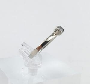 Silver ring with a diamond on stand.