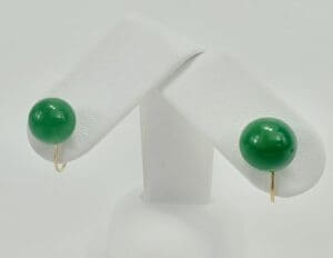 Green stud earrings on display stand.