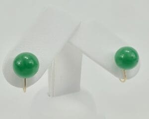 Green jade earrings on white display stand.