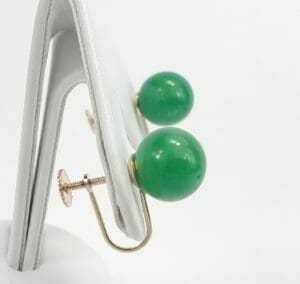 Green jade ball earrings on display stand.