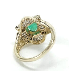 Gold ring with emerald and diamond accents.