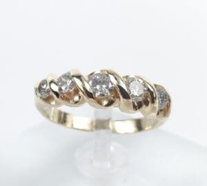 Gold ring with diamonds on display stand.