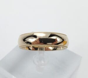 Gold ring with reflective surface on stand.