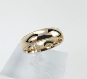 Gold wedding band on display stand.
