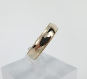 Gold ring on a clear stand.
