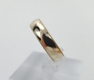 Gold ring with reflective surface on stand.