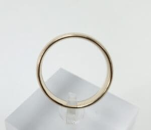 Gold ring on a white display stand.