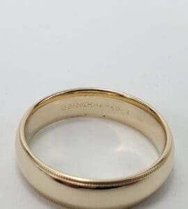 Gold wedding band with engraved interior text.