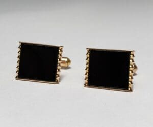 Gold and black square cufflinks on display.