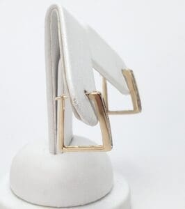 Gold square hoop earrings on display stand.