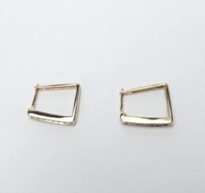 Gold geometric hoop earrings on white background.