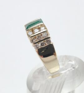 Gold ring with diamonds and green stripe.