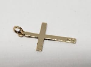 Gold cross pendant on white background.