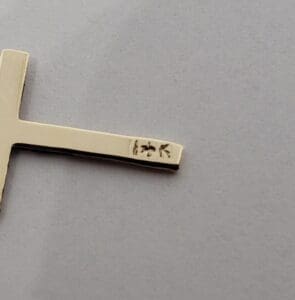 Gold cross pendant with hallmark engraving.