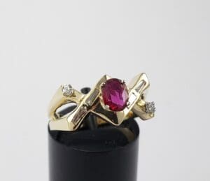 Gold ring with red gemstone and diamonds.