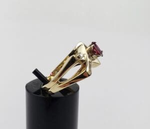 Gold ring with red gemstone on display.