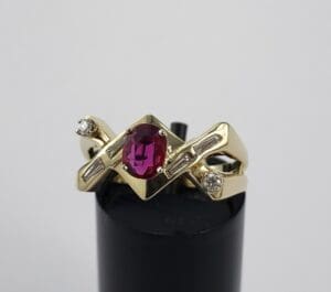 Gold ring with red gemstone and diamonds.