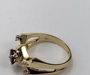 Gold ring with red gemstone and diamonds.