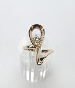 Gold ring with diamond on display stand.