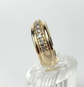 Gold ring with embedded diamonds on stand.