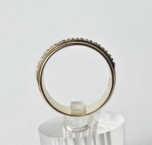 Gold ring displayed on transparent stand.
