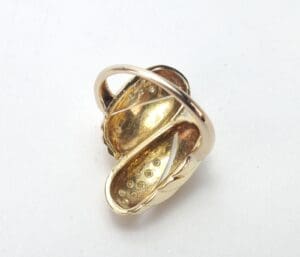 Gold-tone abstract brooch with curved design.