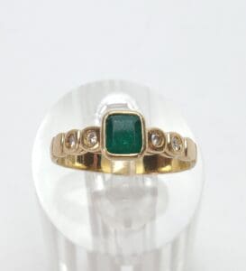 Gold ring with emerald and diamond accents.
