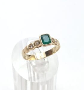 Gold ring with green gemstone and diamonds.