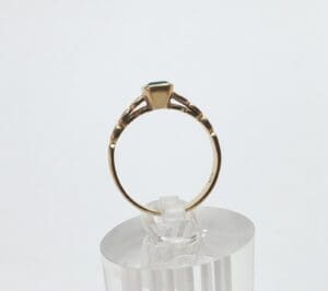 Gold ring with green gemstone on display.
