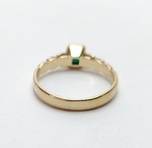 Gold ring with green gemstone on band.
