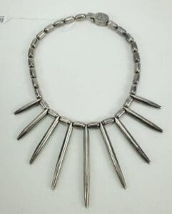 Metallic spiked necklace on white background.